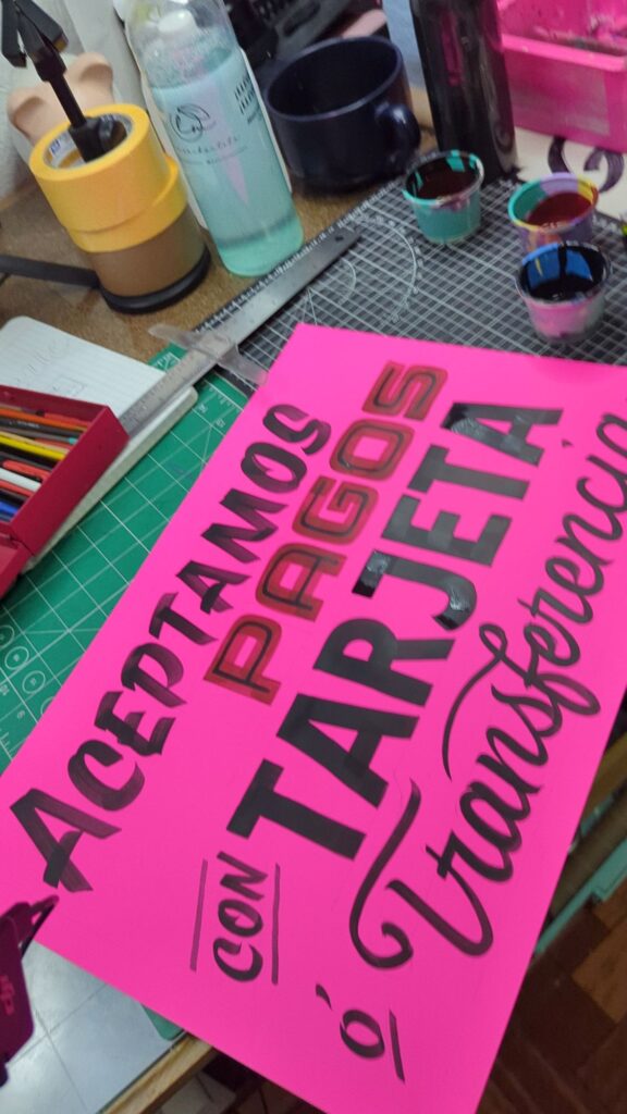 Cartulina fosforescente rosa rotulada a mano: Aceptamos pagos con tarjeta o transferencia