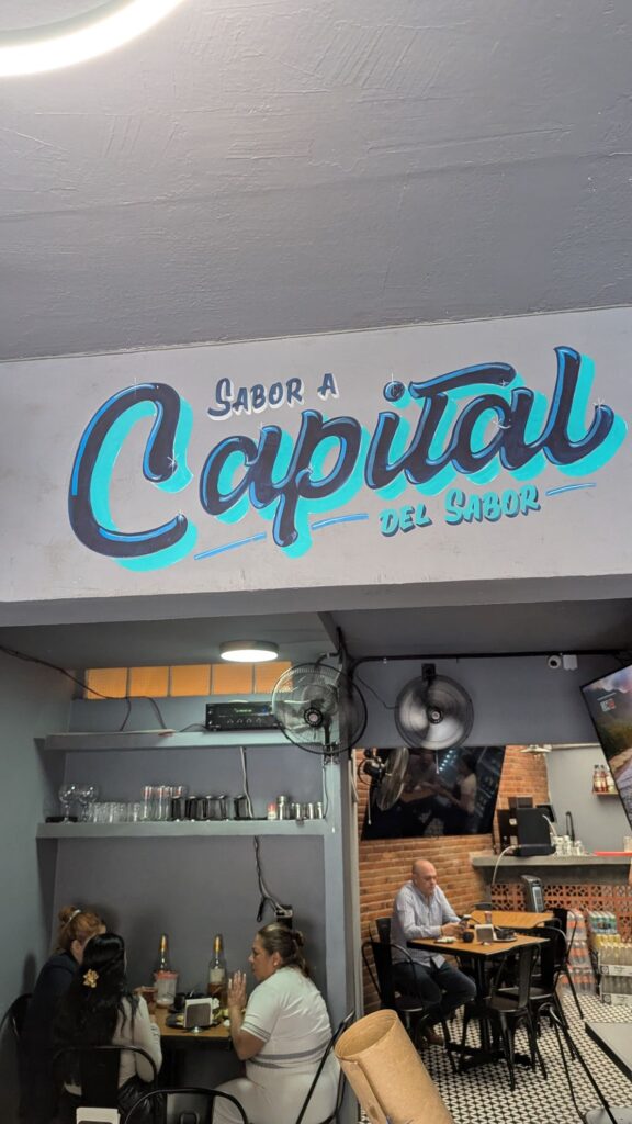 Mural rotulado a mano en un restaurante: Sabor a Capital